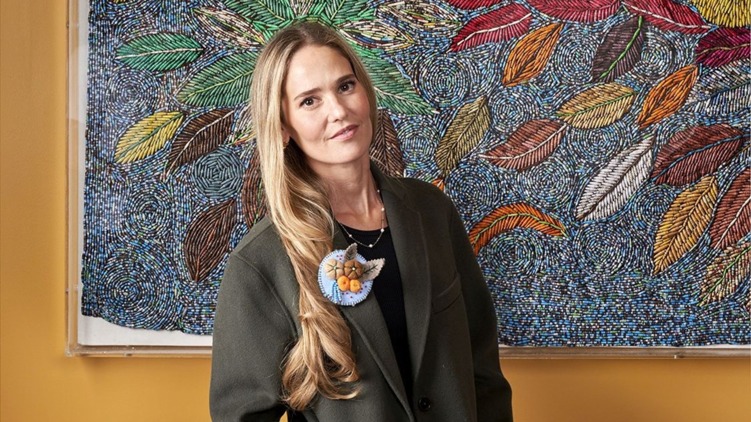 Designer Willow Kemp stood in front of a piece of mosaic artwork 