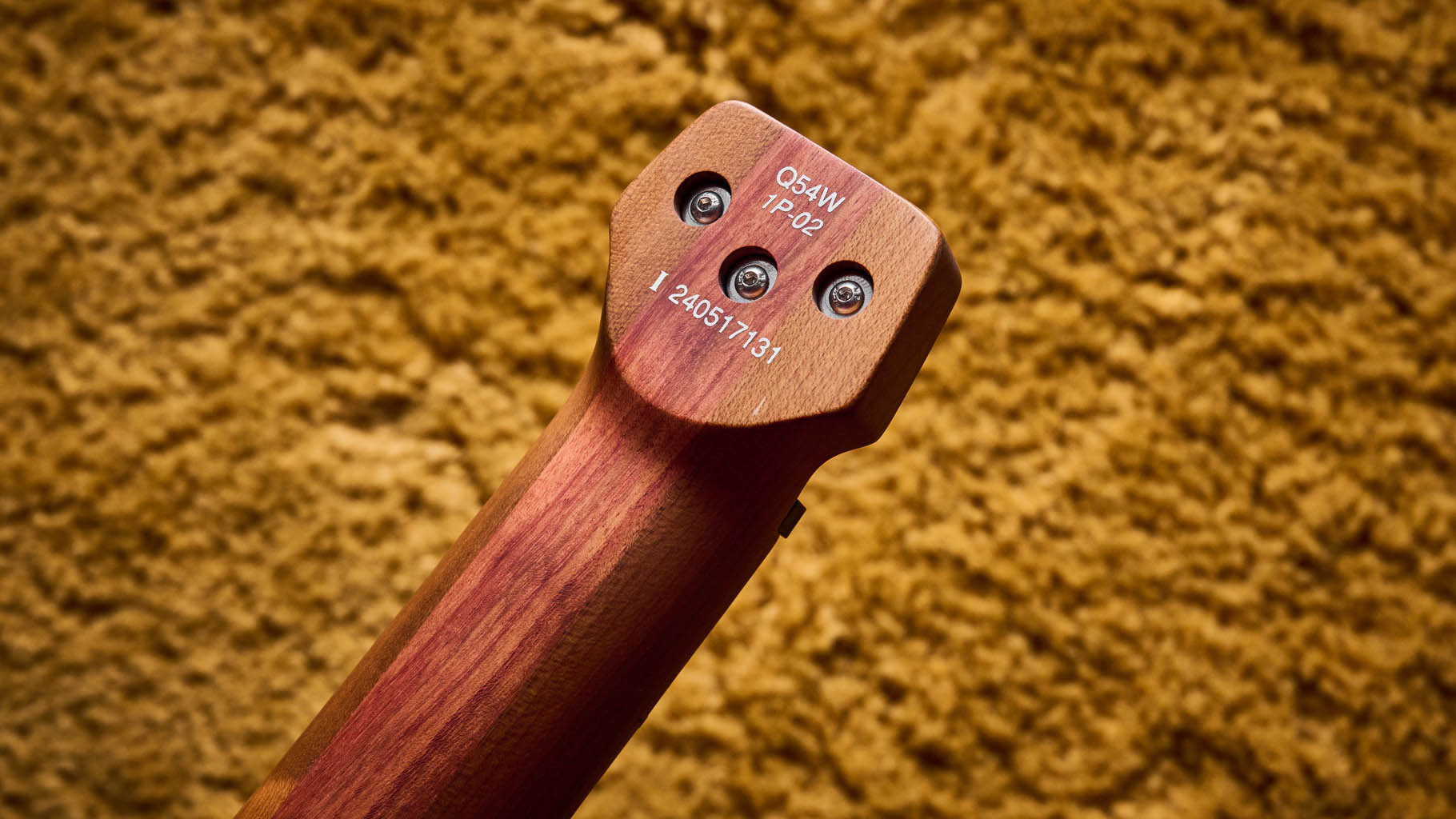 Ibanez Q54W: the headless electric guitar is finished in Copper Metallic Matte and photographed against a thick light-tan colored carpet.