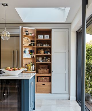 Kitchen with blue and gray cabinets and open pantry door