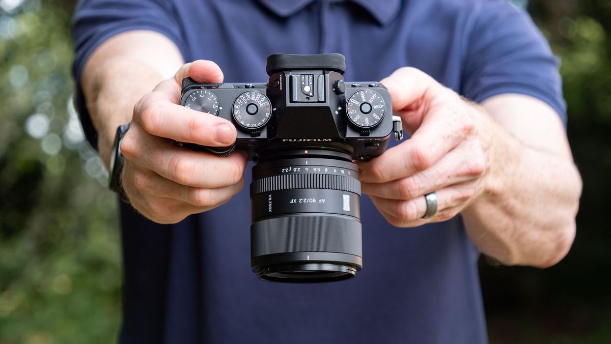Viltrox AF 90mm f/2.2 EVO lens attached to a Fujifilm X-T5 camera, held by tech journalist and pro photographer Tim Coleman