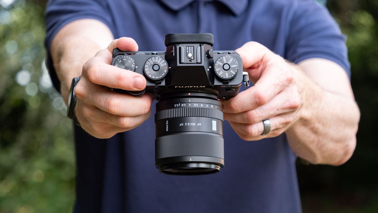 Viltrox AF 90mm f/2.2 EVO lens attached to a Fujifilm X-T5 camera, held by tech journalist and pro photographer Tim Coleman