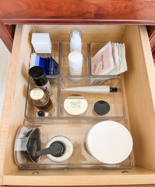 Makeup organized in clear containers inside a vanity drawer