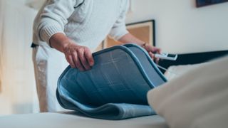 Man folding an electric blanket on the bed