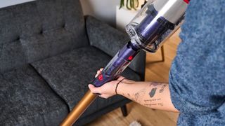 the dyson gen5detect cordless stick vacuum in prussian blue and copper, showing its cleaning head and attachment tools