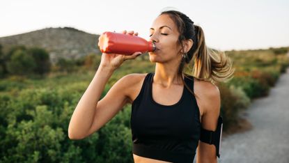 Woman stops for a water break on a run