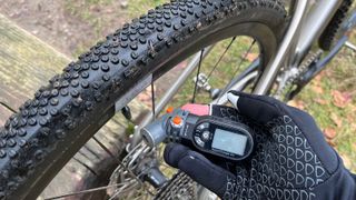 Closeup of tire and hand holding tire pressure gauge