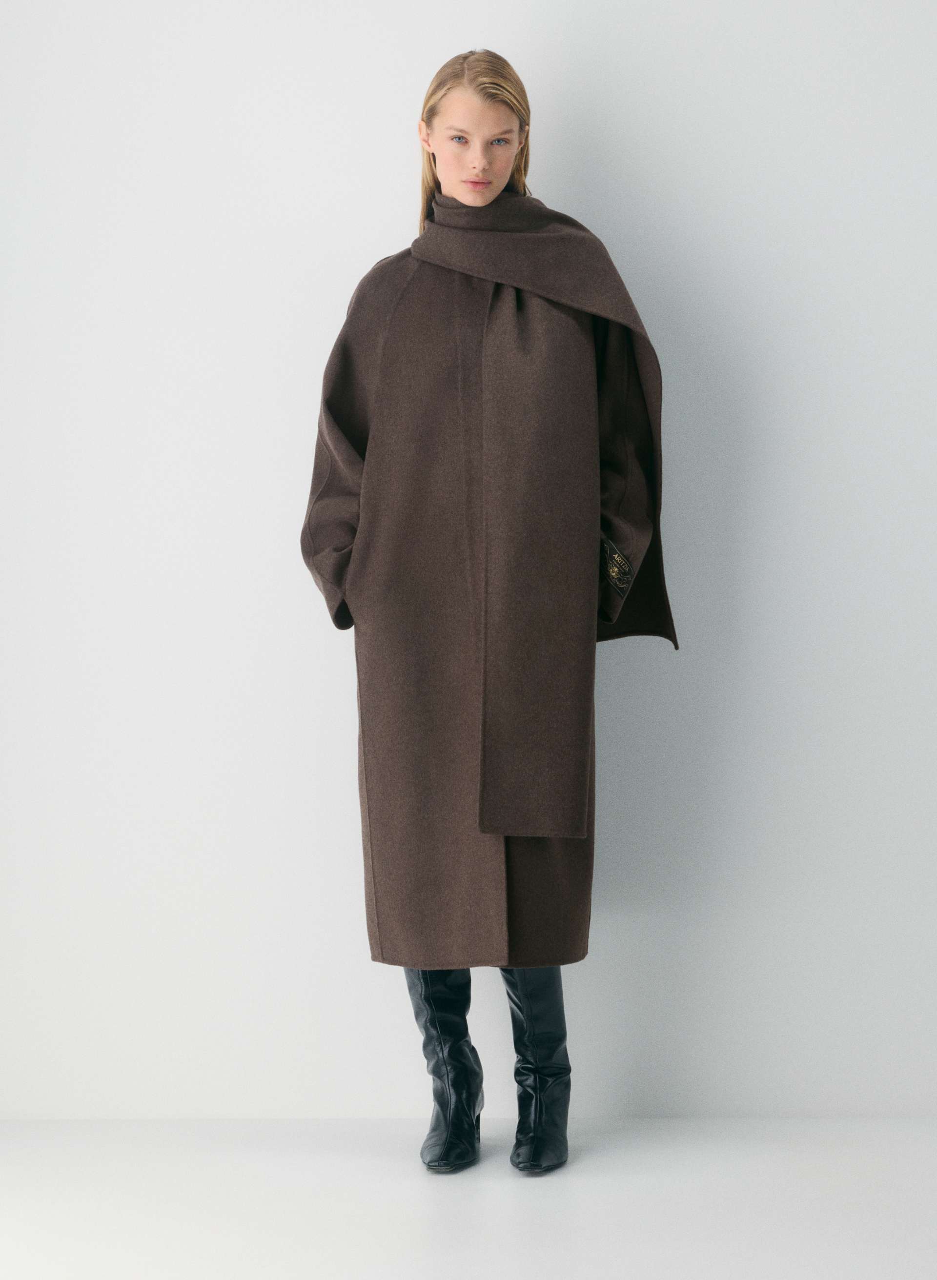 A model wearing a brown double-faced, long wool coat with removable scarf.