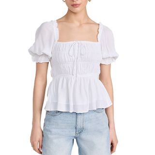 half shot of model wearing white blouse with ruching and light wash jeans