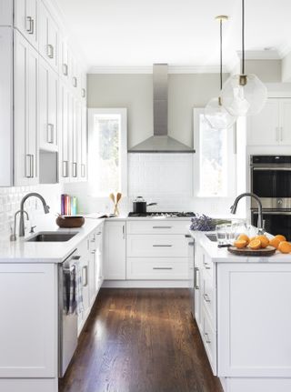 white minimal kitchen with wooden flooring and two sinks