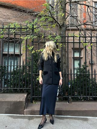 Eliza Huber wearing a black velvet Liberowe blazer with a navy slip dress and black shoes.