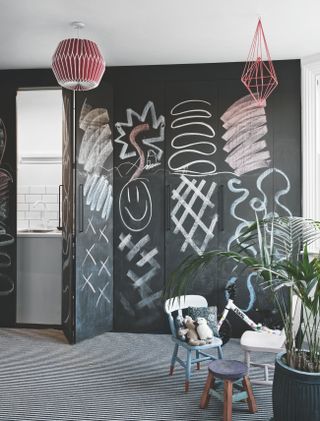 A chalkboard wall in a children's nursery with a concealed storage