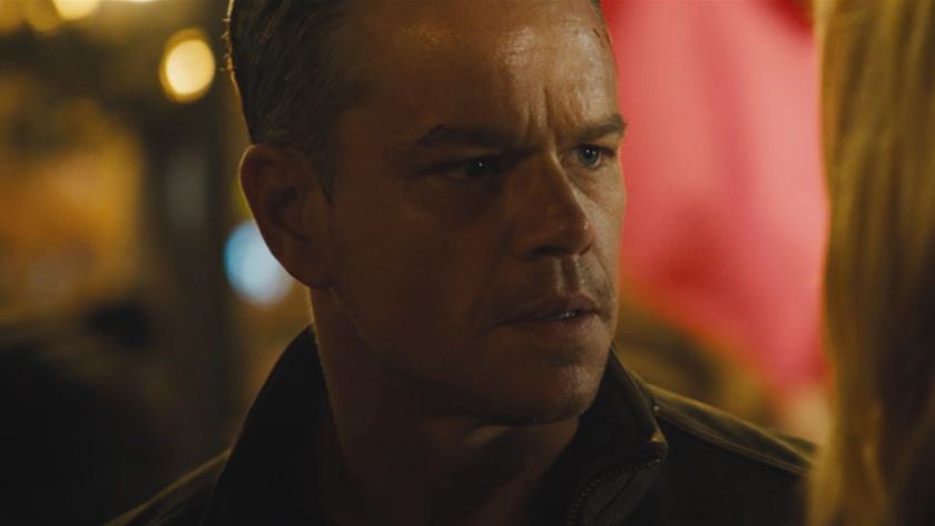 Matt Damon stands in a crowded night scene with a questioning look in Jason Bourne.