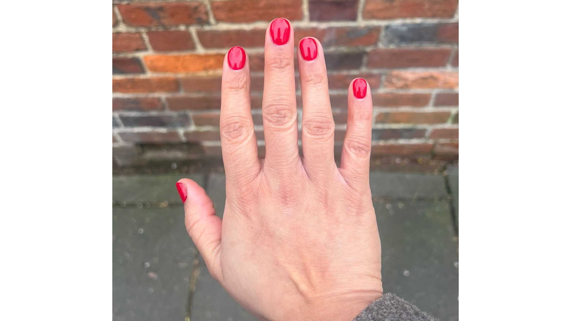 A close-up of Digital Beauty Ecommerce &amp;amp; Shopping Editor, Aleesha Badkar's hand with short, bright red nails