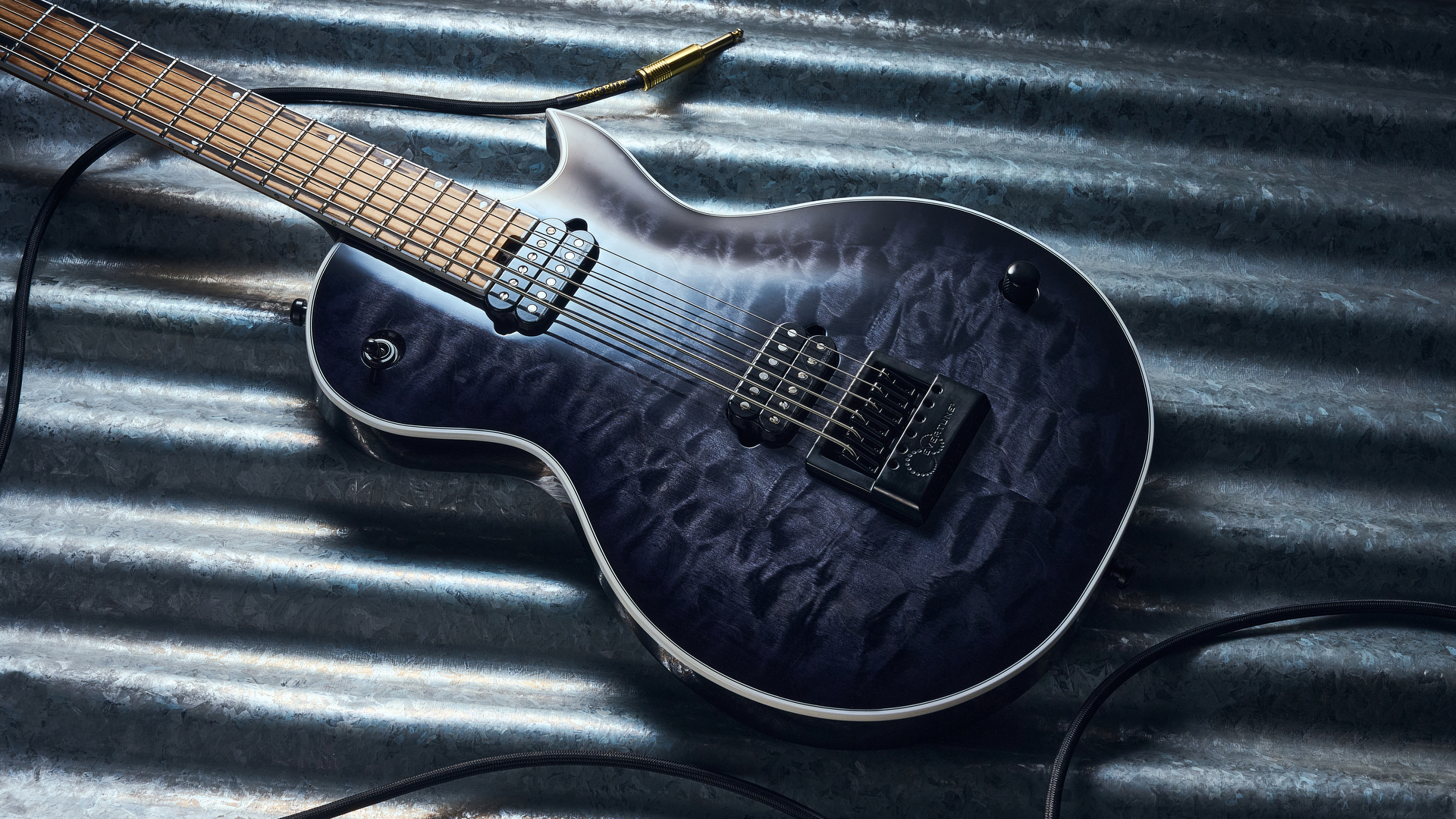 The Jackson Signature Sleep Token IV Monarkh electric guitar lying on a piece of corrugated metal with a guitar cable coiled nearby