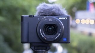 Kameraet Sony ZV-1 festet til et stativ utendørs med utsikt over en elv.