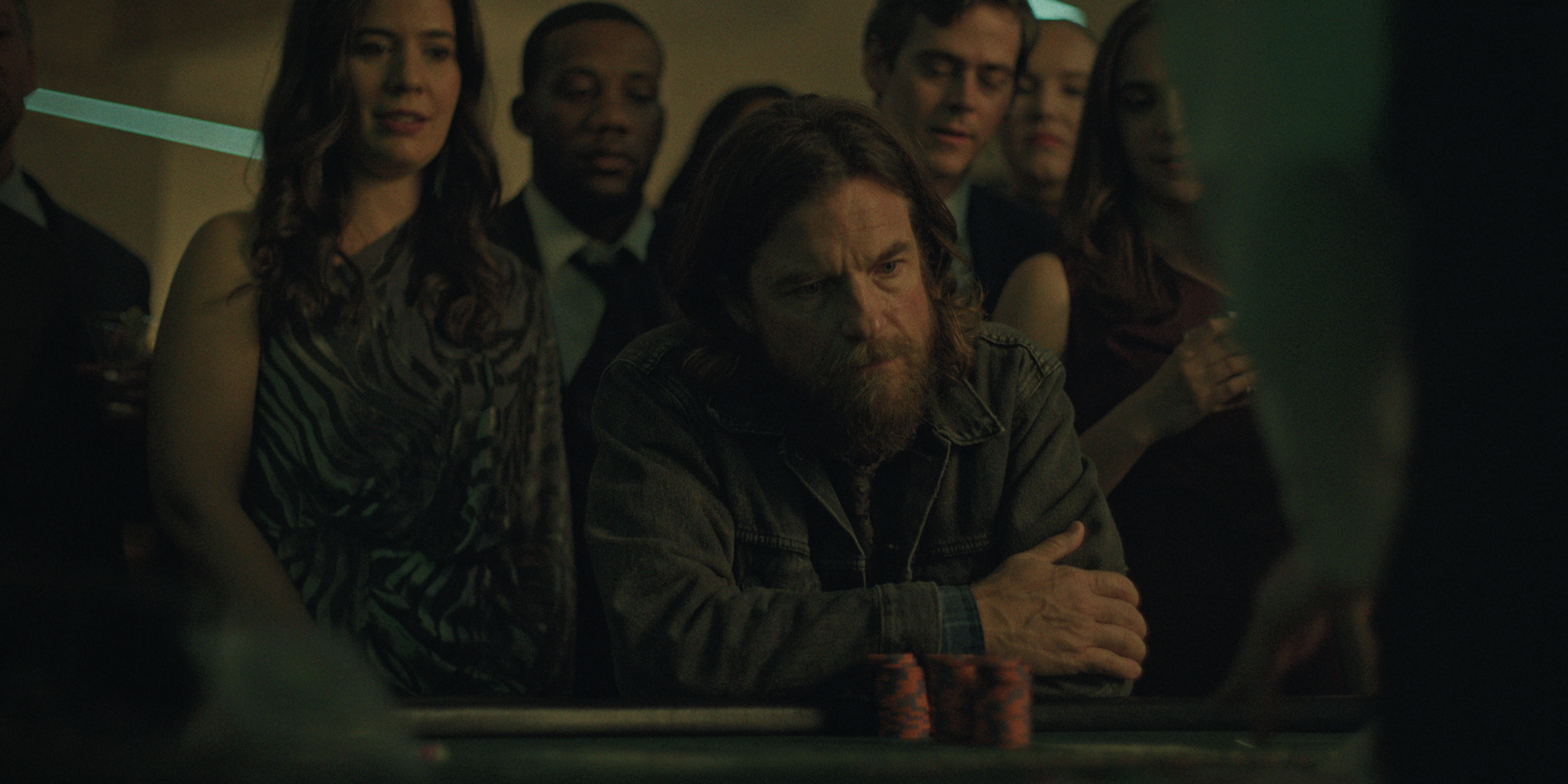 jason bateman as Vince Friedken looking scruffy sitting at a table at a crowded bar in black rabbit
