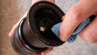 Cleaning a camera lens with a microfiber cloth.