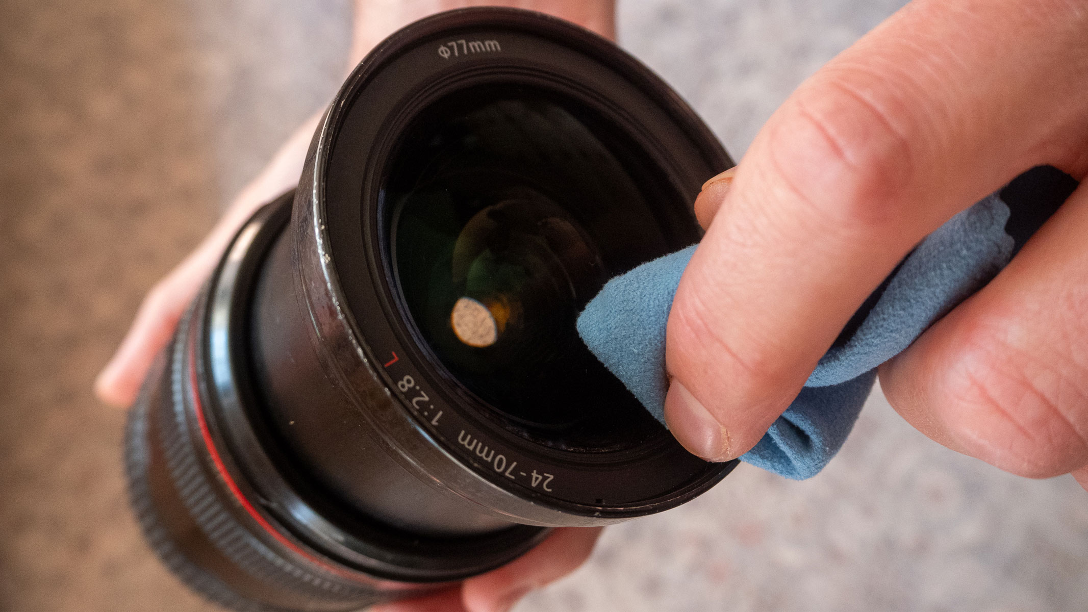 Cleaning a camera lens with a microfiber cloth.