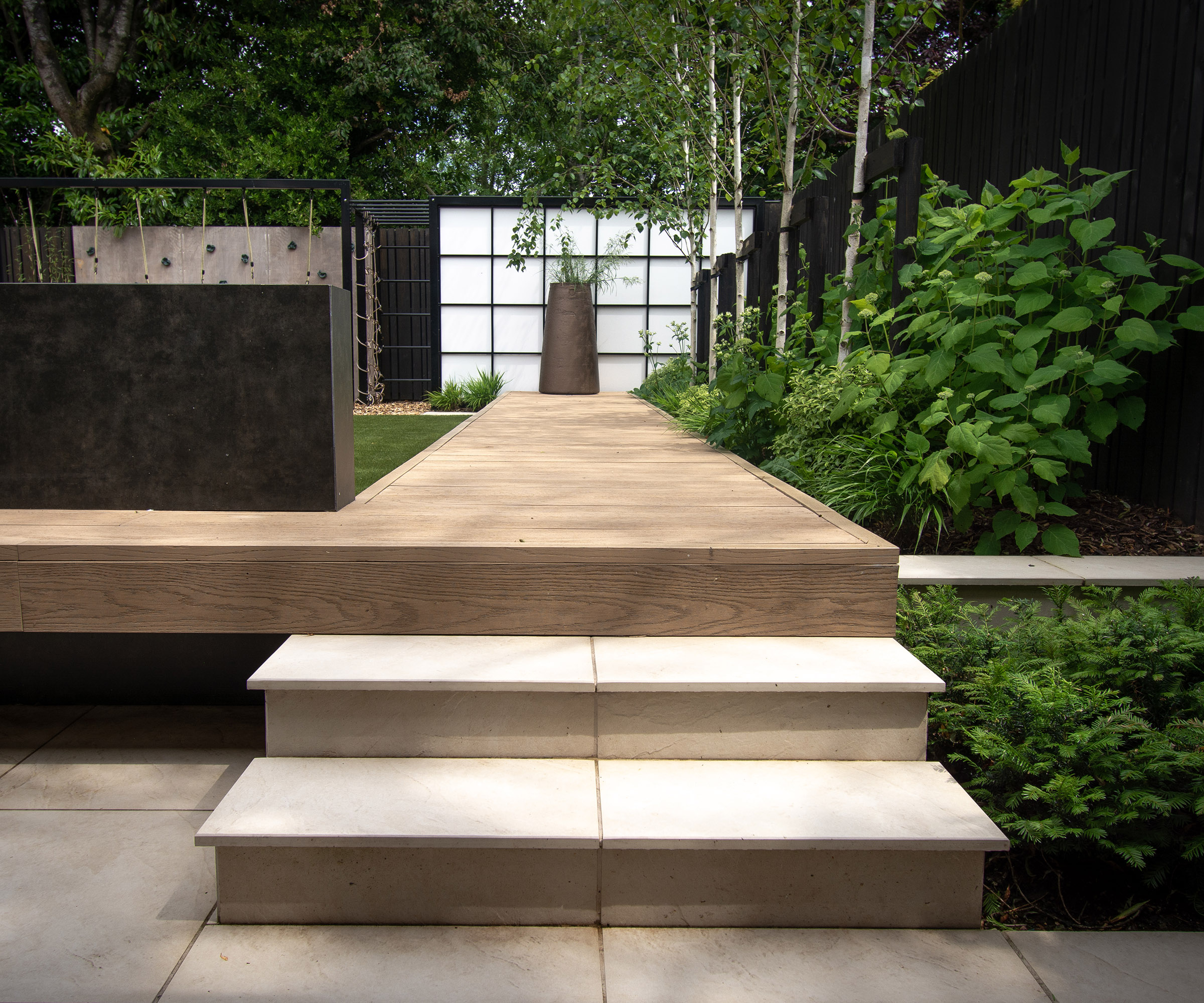 Garden steps leading up to a path with decorative screen