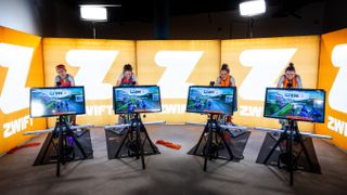 Zwift finalist indoor testing with four large tv screens showing zwift