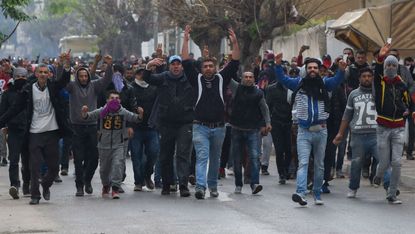 Tunisian protesters gesture towards police