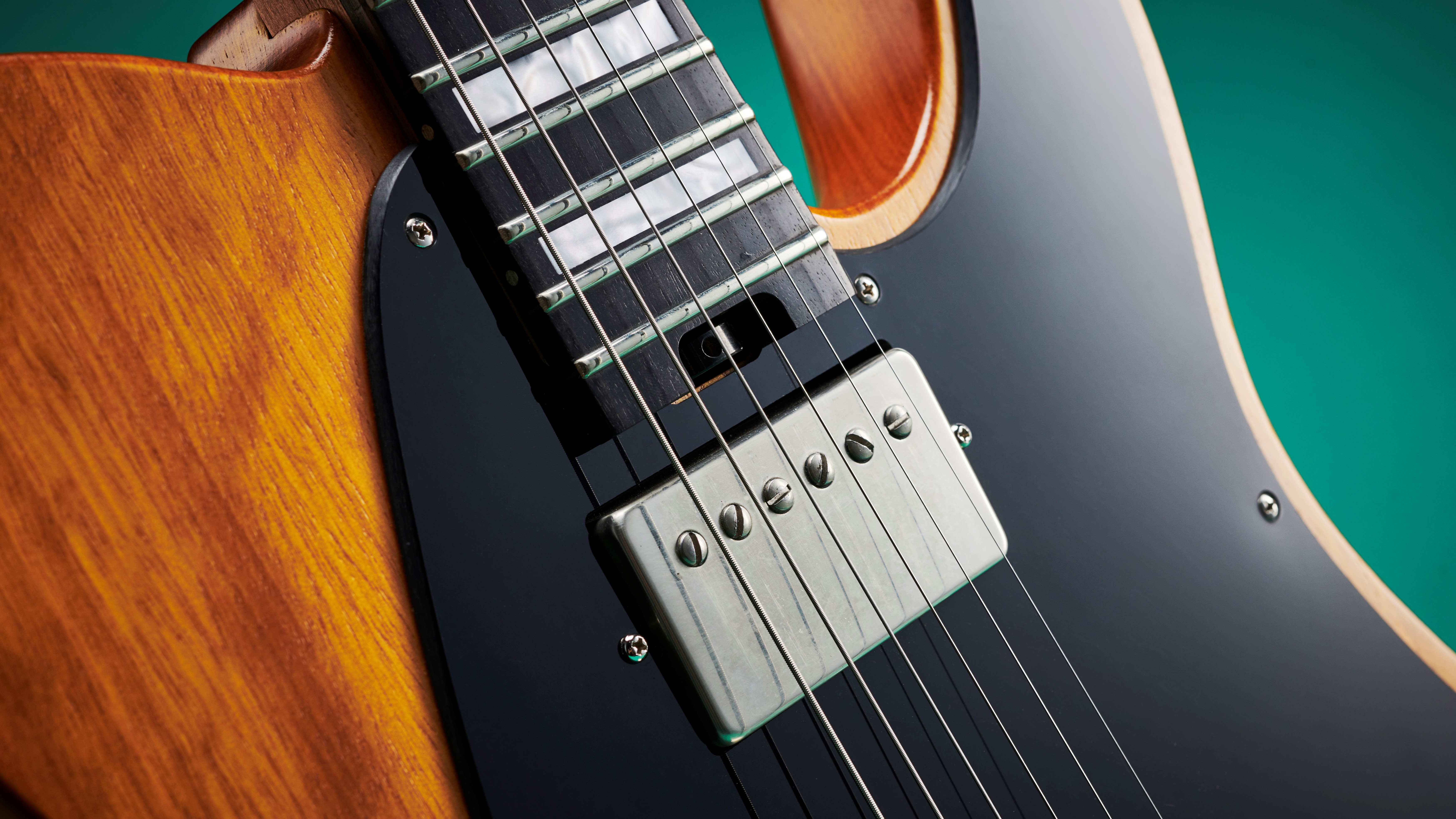 Close-up of the neck humbucker of the Charvel Joe Duplantier signature model on a dark grey background