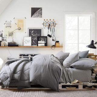 Pottery Barn Dorm bedroom with a grey bed and wall shelves with black accents