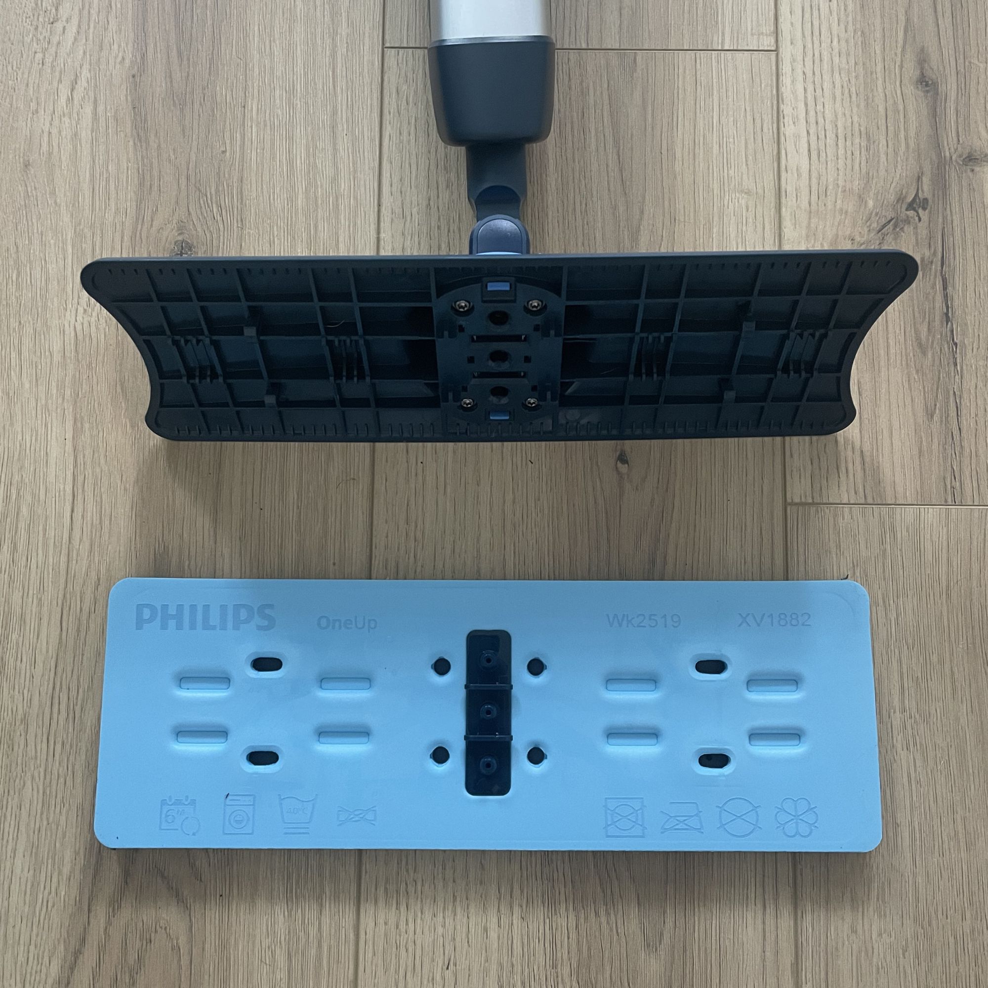 Close up of the mop head of the Philips OneUp Electric mop, with the mop head detached and sitting on wood-efffect flooring