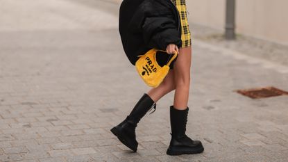 Trixi Giese wearing Prada yellow bag, black vintage bomber jacket, Urban Outfitters black top, Zara yellow skirt and black combat boots on August 17, 2021 in Berlin, Germany. 