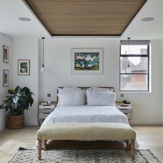 Main bedroom with wooden flooring, white bedding and wooden ceiling recess