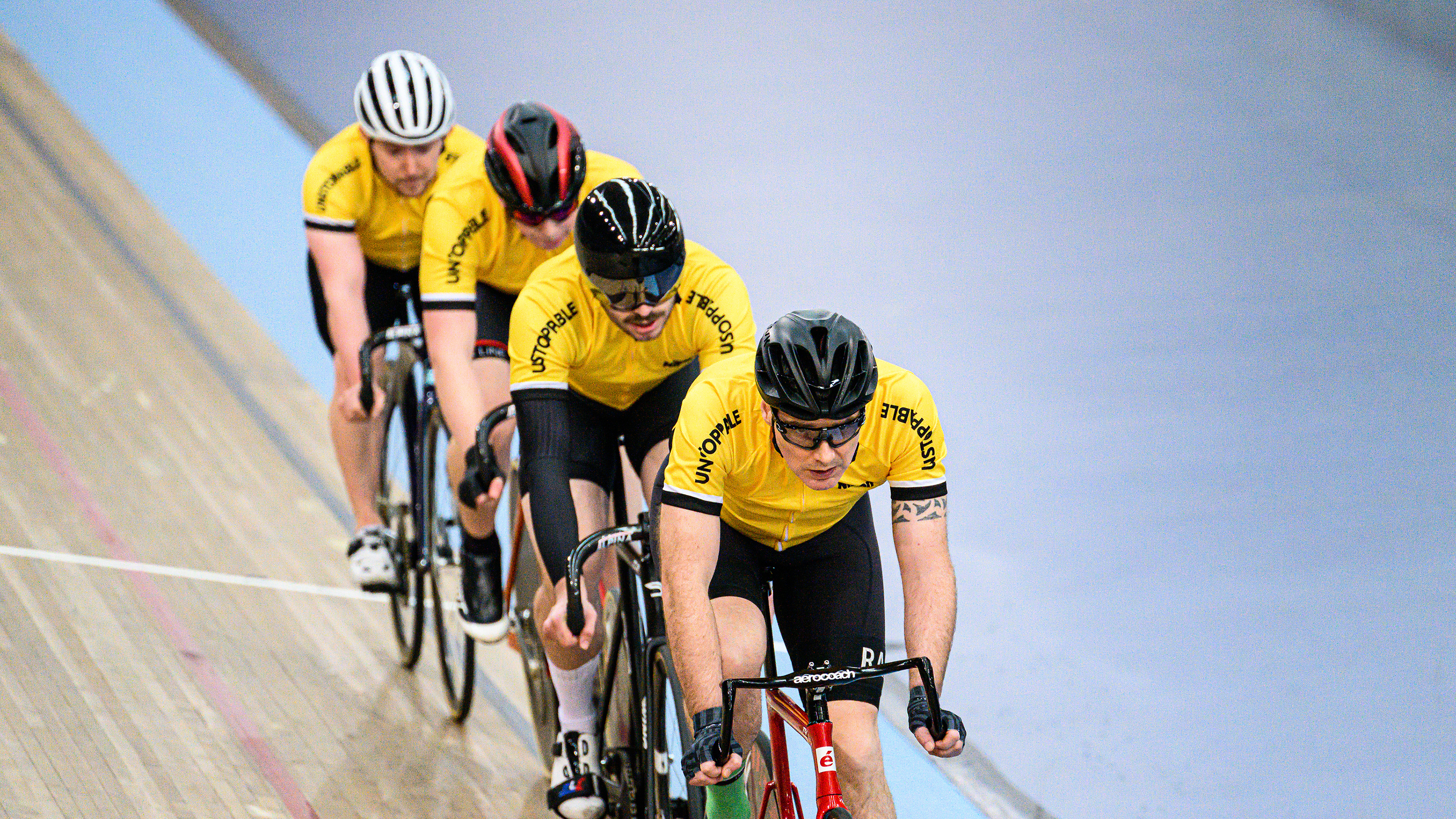 Cuatro ciclistas dando vueltas por un velódromo