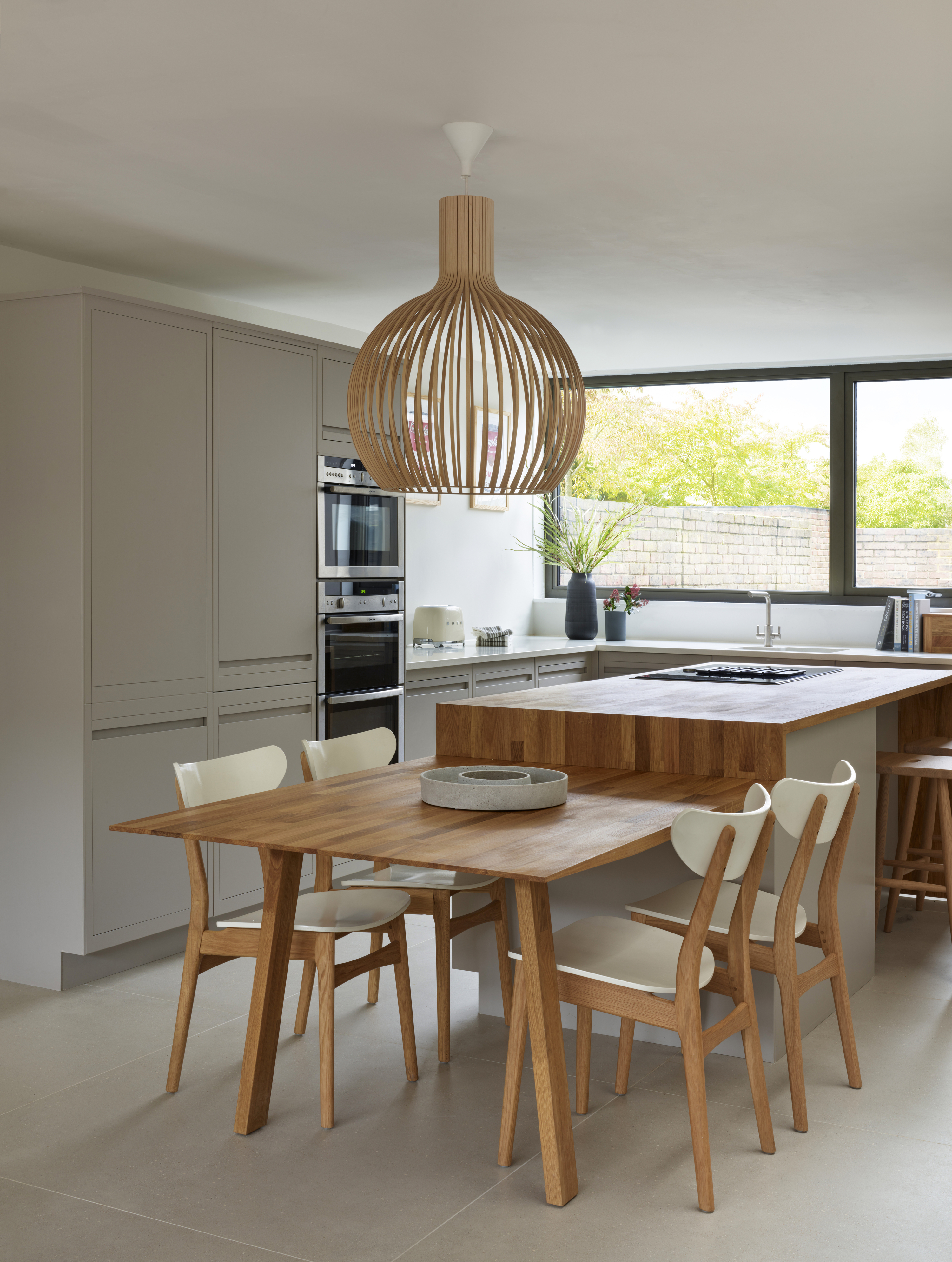A kitchen with wooden seating, a wooden island and handleless cabinets all in grey