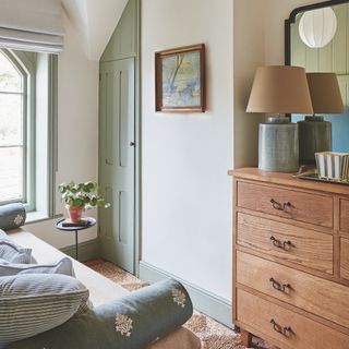 Small bedroom with single divan daybed and wooden chest of drawers with large lamp