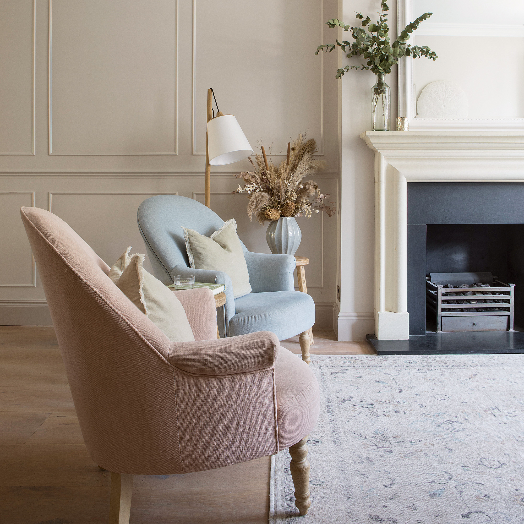 neutral living room with two pastel coloured armchairs and fireplace