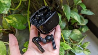 UGREEN HiTune T3 ANC earbuds and case held in the palm of a hand