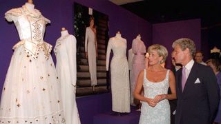 Princess Diana looking at a white gown she is auctioning off for charity in a showroom