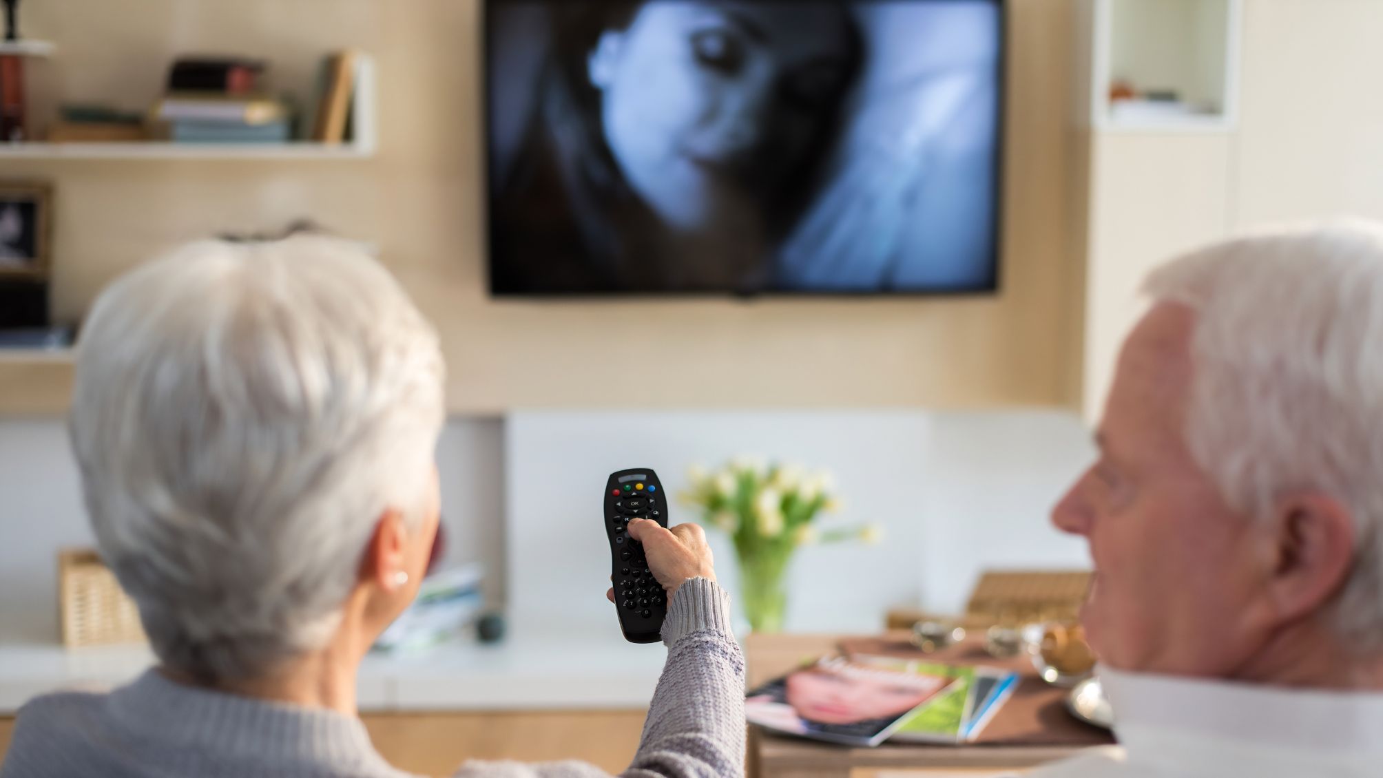 A couple sitting on a couch and watching tv. 