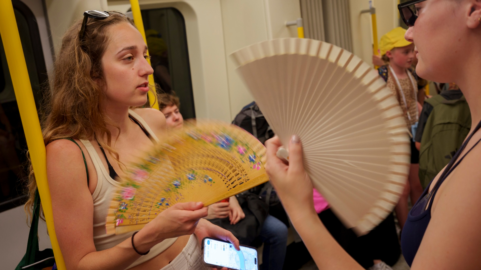As the hottest ever day in June is recorded with the breaking of a fifty-year record of 36 degrees Celcius recorded in southern England, two women use fans on a tube train
