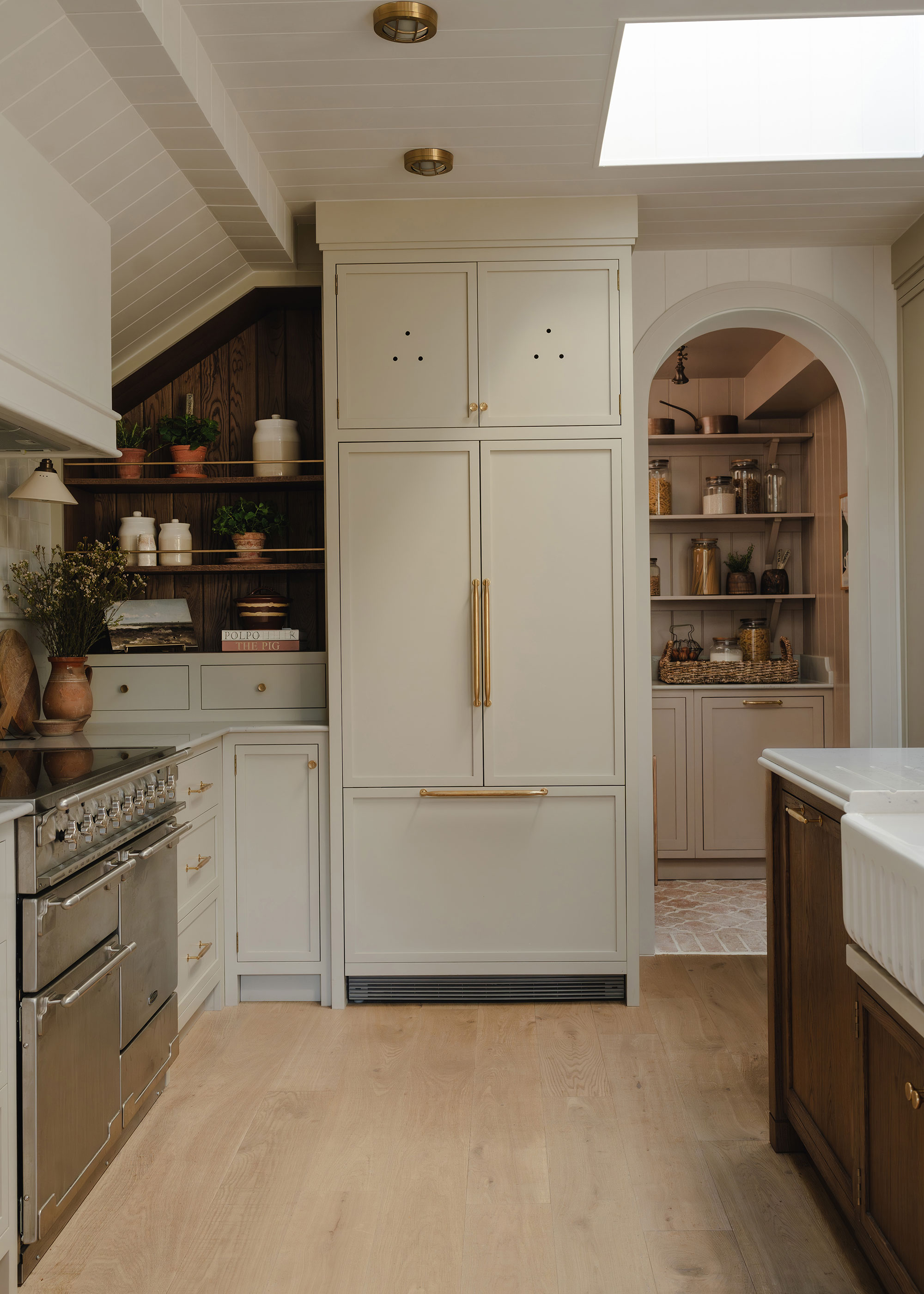 modern neutral kitchen with pale wooden flooring and archway through to back kitchen