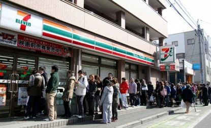 Japanese residents queue up in an orderly fashion outside a 7 eleven.
