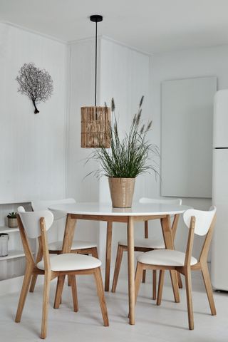 round dining table with white chairs in space with white walls and white shelves