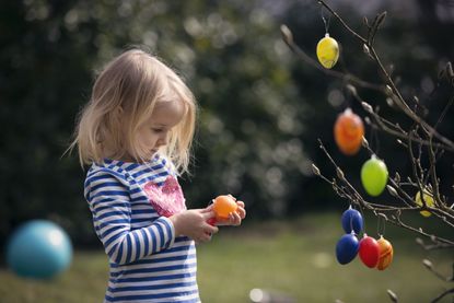 Child decorating tree with easter eggs, after finding out when Easter 2021 is