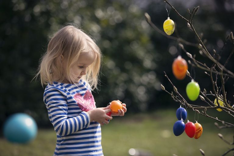 Child decorating tree with easter eggs, after finding out when Easter 2021 is