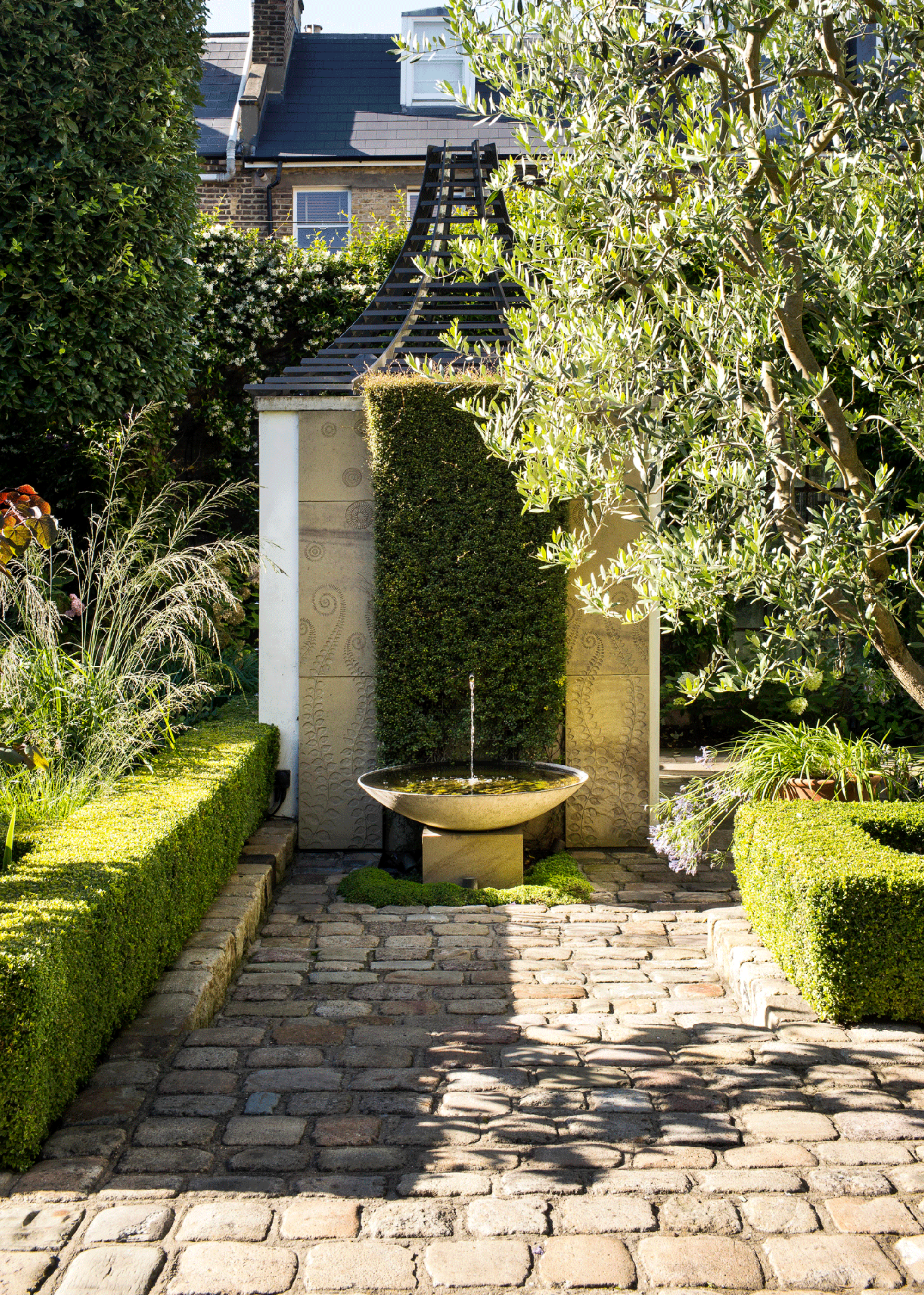 a mediterranean courtyard garden with box hedges and a water fountain bowl