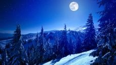 A full moon shines over a snowy mountain.