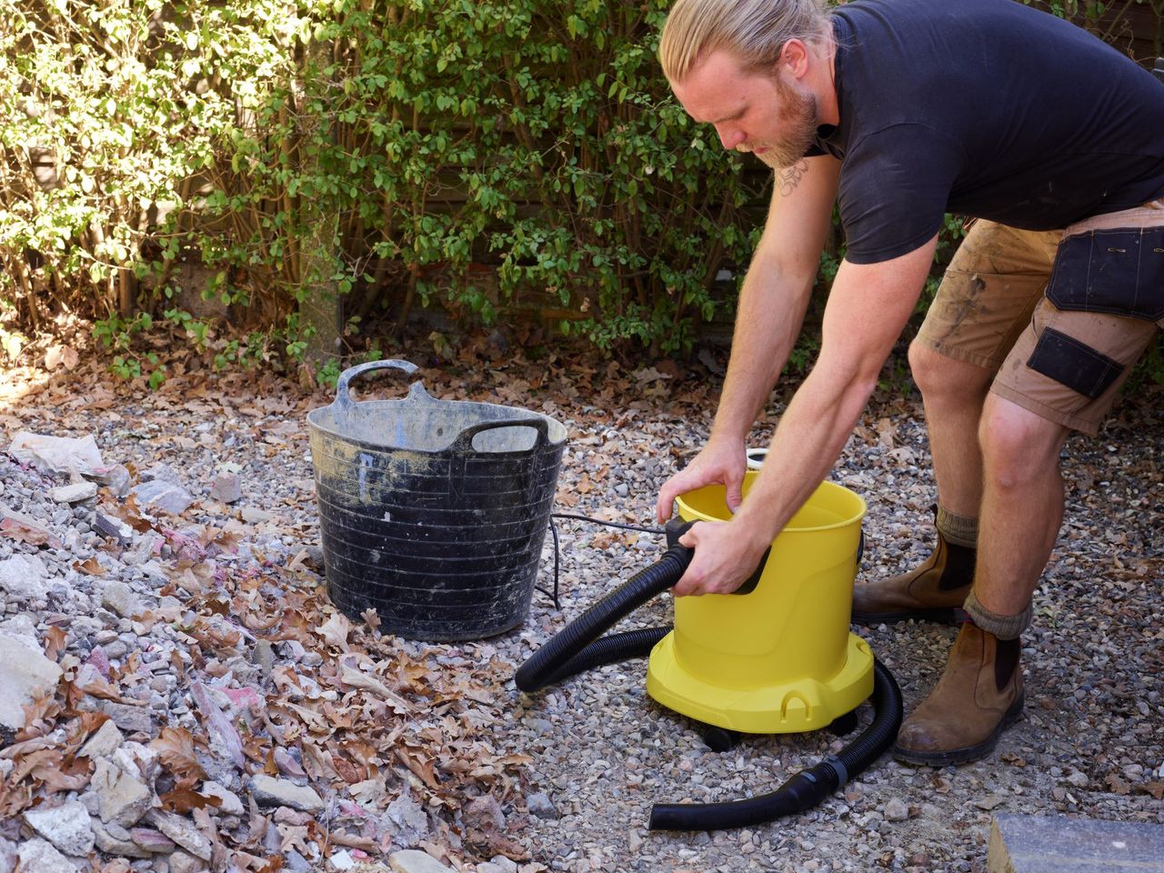 A builder lifts the K&auml;rcher WD vacuum ready to empty it