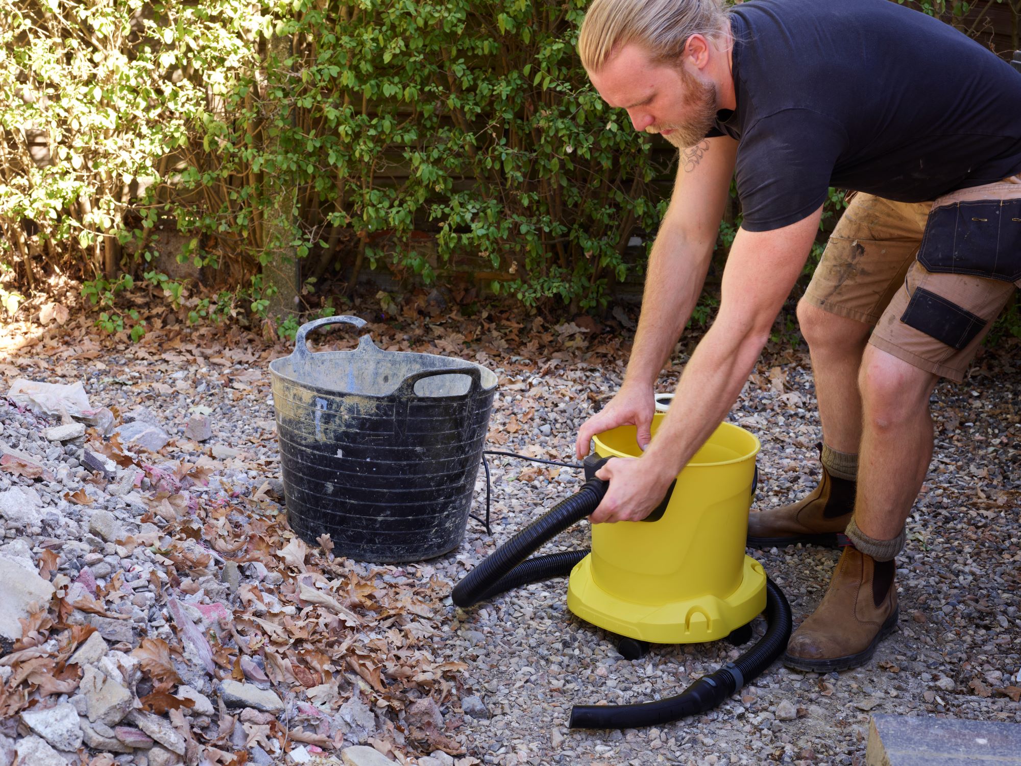 A builder lifts the Kärcher WD vacuum ready to empty it
