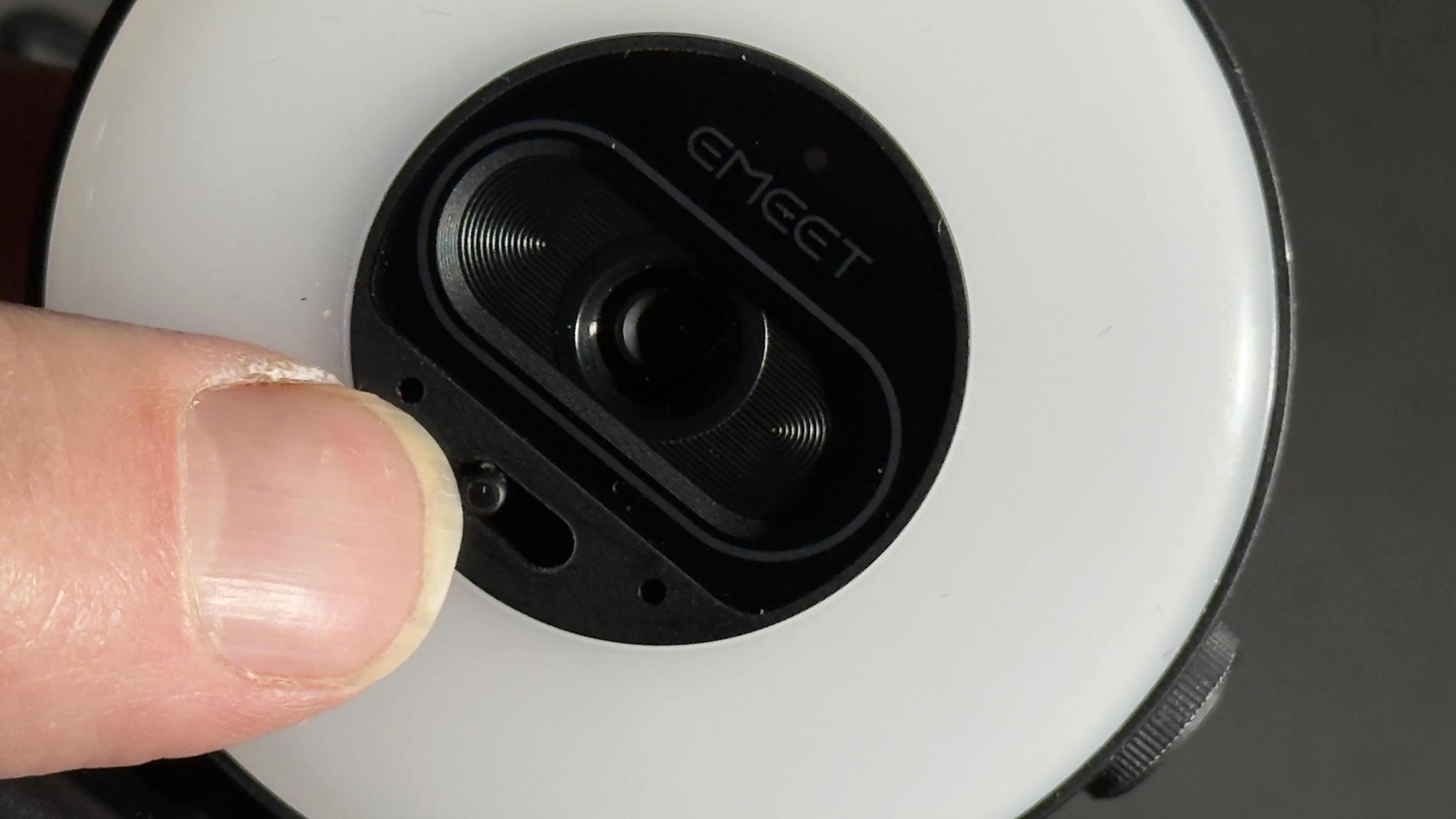 Close-up of a finger moving the privacy shutter control beneath the EMEET webcam lens.