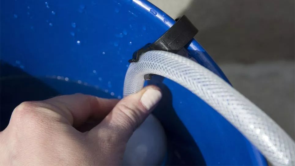 The WORX Hydroshot WG629 water supply hose being clipped to the side of a blue bucket