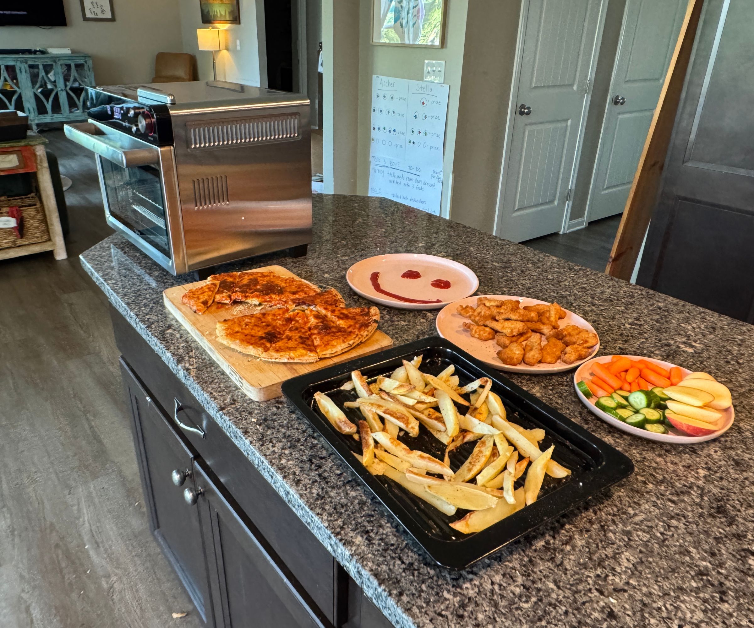 A selection of fried foods including cheesy pizza and fries on trays on a granite worktop